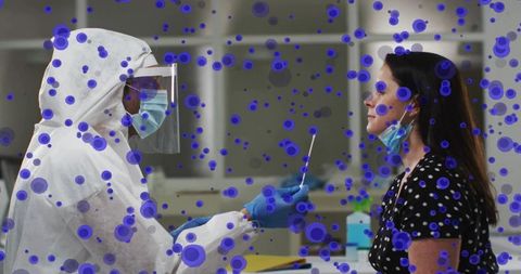 Healthcare worker testing patient with nasal swab in full PPE with purple particle overlay