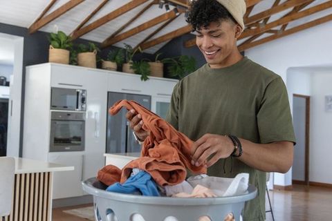 Young african american man sorting laundry in bright modern open-plan kitchen