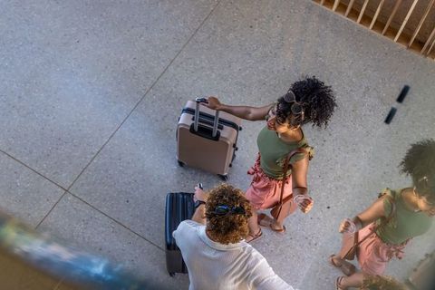 Overhead view of couple walking with rolling suitcases through modern terminal concourse