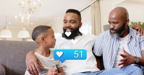 Multigenerational family bonding on sofa, dad and grandfather chatting with son at home