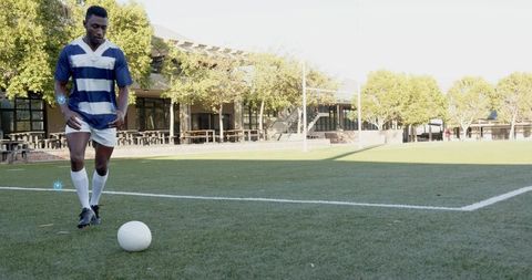 Soccer player preparing to kick ball on sunlit campus turf with ample copy space