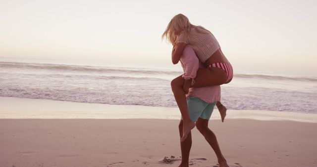 Happy diverse couple playing piggy back on beach - Download Free Stock Photos Pikwizard.com