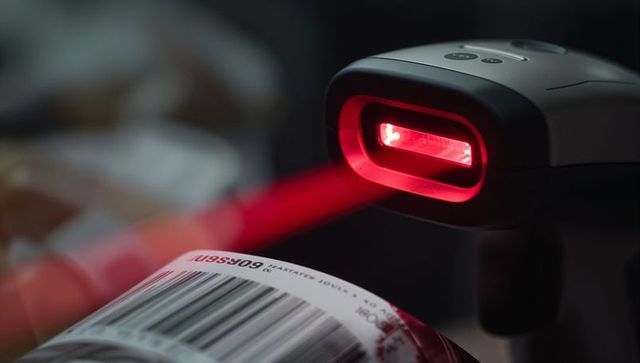 Retail barcode scanner scanning red laser across curved can barcode at checkout counter