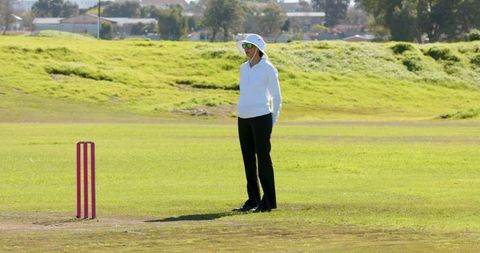 Female cricket umpire on sunny field