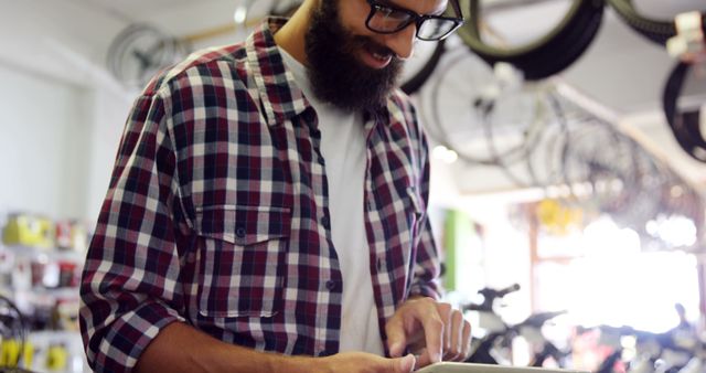 Bearded man using digital tablet in bicycle shop - Download Free Stock Images Pikwizard.com