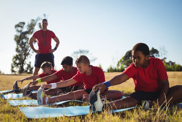 Kids are performing stretching exercises under guidance of a trainer in an outdoor boot camp. Ideal for illustrating fitness programs, children's physical education, group workouts, and promoting healthy lifestyles. Useful for educational materials, health and wellness blogs, and fitness advertisements.