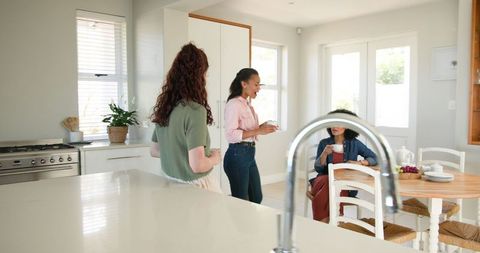 Three Friends Socializing at Baby Shower in Bright Home Kitchen