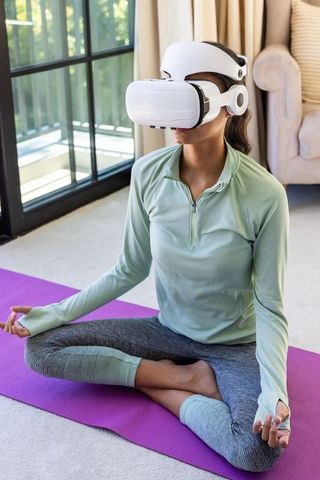 Woman practicing vr meditation on yoga mat at home for mindfulness and wellness