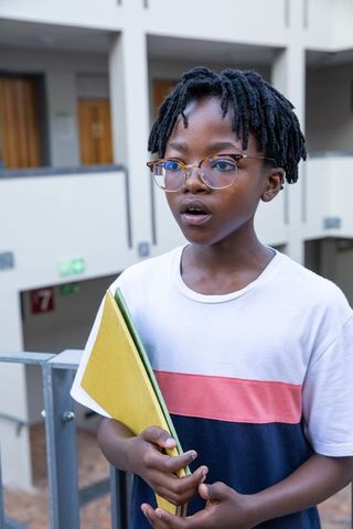 Young student holding notebooks in school hallway