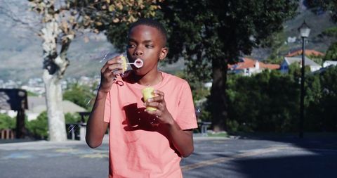 Youthful boy blowing bubbles in sunny park
