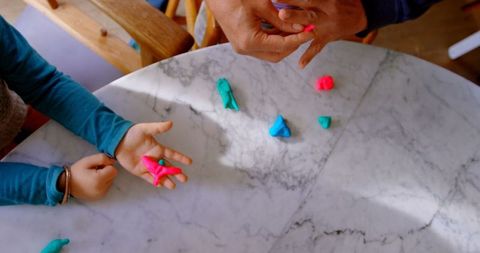 Father and children creating with colorful clay at marble table