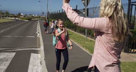 Teacher greeting elementary students on sunny walk to school