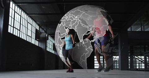 Two athletes jumping rope inside industrial warehouse with translucent globe overlay