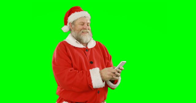 Santa Claus in traditional red suit is using a smartphone against a green screen background. Perfect for holiday-themed projects, social media content, or promotional materials. The green screen makes it easy to replace the background with your desired image or video.