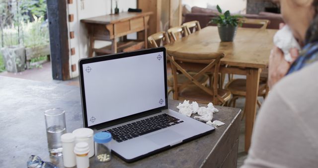 Sick person using laptop at home with medicine bottles on table - Download Free Stock Images Pikwizard.com