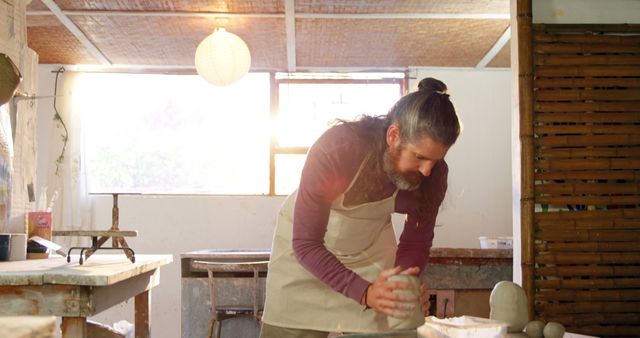 Man Creating Pottery in Sunlit Workshop - Download Free Stock Images Pikwizard.com