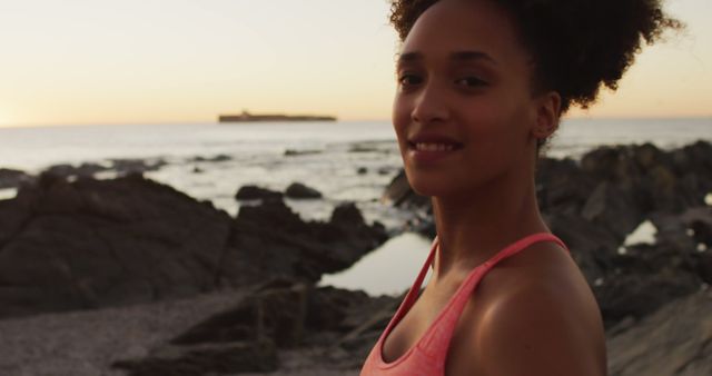 Smiling Woman Training Outdoors on Rocky Beach at Sunset - Download Free Stock Images Pikwizard.com