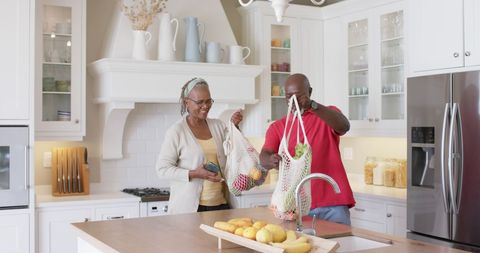 Senior African American Couple Unpacking Groceries in Modern Kitchen