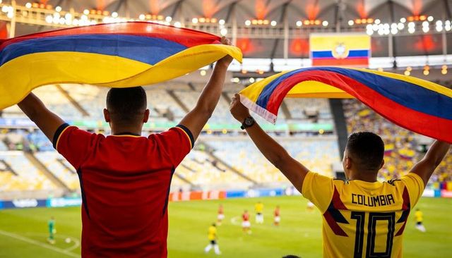 Colombian fans waving tricolor flags and cheering in stadium during football match