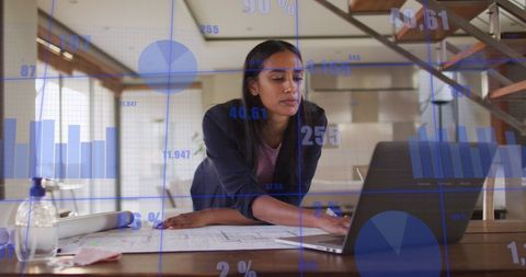 Businesswoman Engaging in Data Analysis with Laptop and Charts