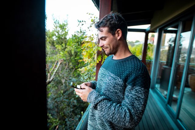 Smiling caucasian man standing in patio, using smartphone - Download Free Stock Photos Pikwizard.com