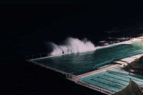 Waves crashing over illuminated night pool
