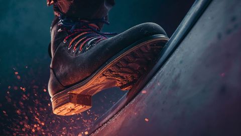 Heavy-duty leather boot scraping curved metal rail sparking workshop closeup action