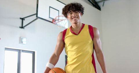 Young Athletic Man Smiling Confidently Holding Basketball in Gym