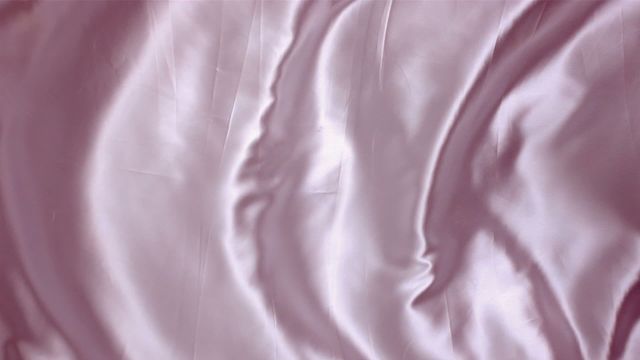 Pink satin fabric is shown in an elegant manner with subtle waves, showcasing the fluid texture and shimmering quality of the material. It creates a soft and refined view perfect for illustrating luxury, romance, and delicacy themes. This image can be used for backgrounds, textile-related designs, interior decor promotions, and fashion showcases.