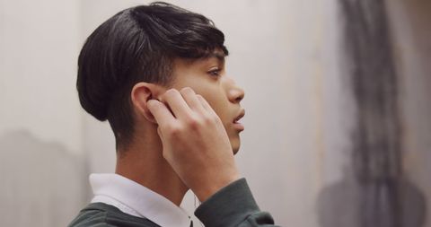 Transgender Biracial Man Adjusting Earphones in Urban Setting