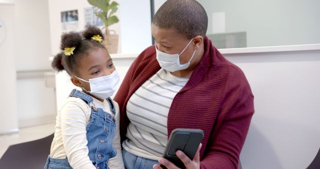 Mother and Daughter Wearing Face Masks Sitting in Clinic Waiting Room - Download Free Stock Images Pikwizard.com