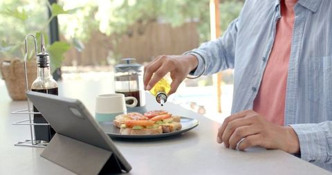Man Preparing Breakfast with Tablet: Pouring Olive Oil on Toast