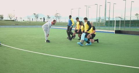 Men's Field Hockey Team Training on Turf with Coach