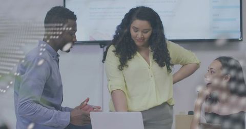 Leader presenting data while team collaborating around laptop in bright office conference room