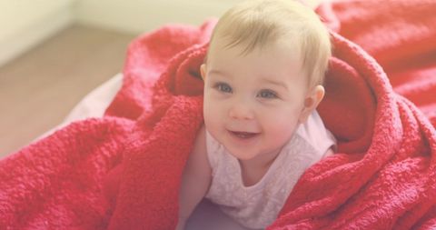 Smiling Baby Wrapped in Cozy Red Blanket