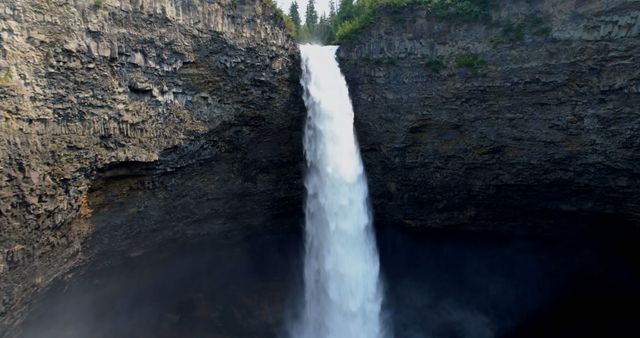 Majestic waterfall cascading into a deep canyon with mist forming near the base. Ideal for nature-related content, travel blogs, environmental articles, and adventure advertisements.