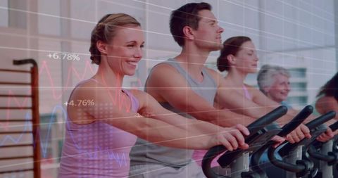 Mixed-age group pedaling on stationary bikes in spin class with fitness metrics overlay