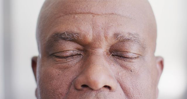 Mature man eyes closed meditating, showing deep relaxation and mindfulness. Ideal for themes of health, well-being, mindfulness practice, mental wellness, yoga guidance, or relaxation strategies.