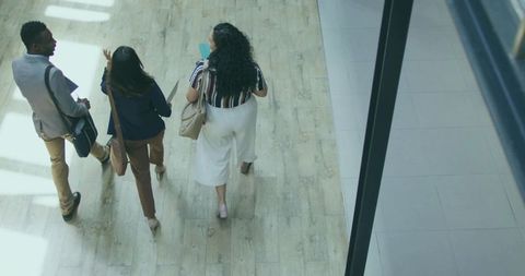 Team of Professionals Walking Through Office Corridor in Formal Wear