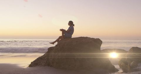 Woman Reflecting During Sunset Beach Scene with Lens Flare