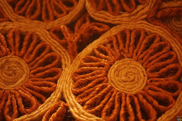 Detail of handmade woven straw coasters with circular patterns. Great for illustrating topics related to traditional crafts, eco-friendly products, and rustic home decor. Ideal for use in lifestyle blogs, eco-conscious product listings, or art and craft content.