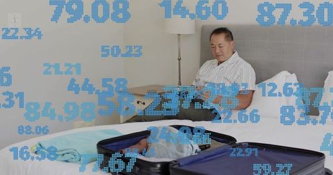 Middle-aged man relaxing in hotel room using phone beside open suitcase with data overlay