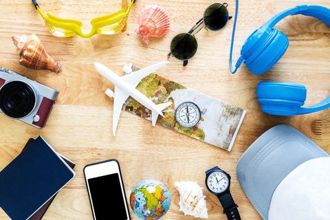 Flat lay travel planning featuring airplane model, passport, compass, camera and beach gear