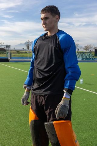 Teen Field Hockey Goalie Standing on Turf Ready for Action