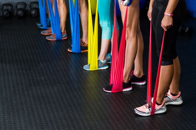 Athletes are using resistance bands for leg exercises in a fitness studio. This image is ideal for promoting group fitness classes, gym memberships, workout routines, and strength training programs. It highlights the use of exercise equipment and the importance of an active lifestyle.