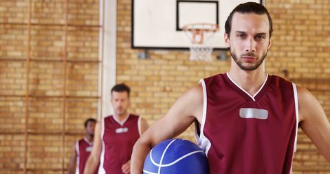 Focused basketball player holding ball on indoor court