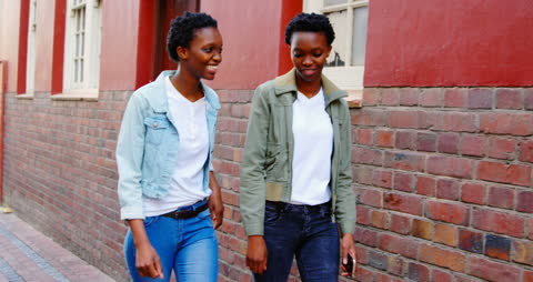 African Twins Enjoying City Walk Focused on Mobile Connectivity
