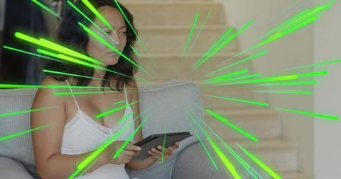 Calm woman holding tablet on sofa with neon green streaks radiating through room