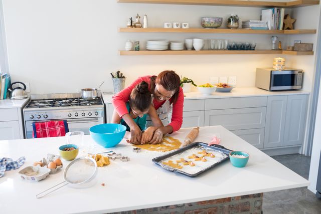 Mother and daughter preparing cookies in kitchen worktop at home