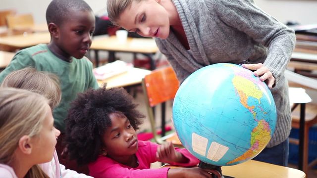 A diverse group of young students gathered around a globe as their teacher explains geographical concepts. This engaging educational setting promotes multicultural learning and sparks curiosity about the world. Useful for illustrating interactive teaching methods, promoting global education initiatives, or featuring diverse learning environments in educational materials or campaigns.